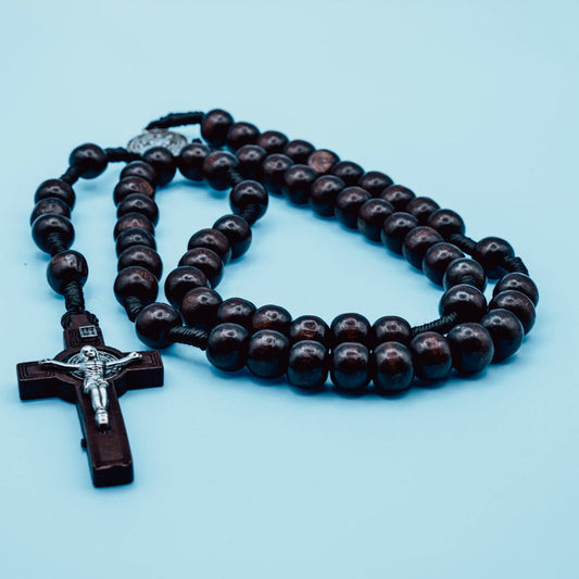 Wooden rosary with a cross on a light blue background