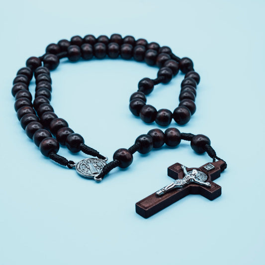 Wooden rosary with a cross on a light blue background